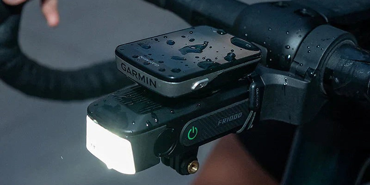 Luz delantera Ravemen FR1000 encendida y montada en el manillar de una bicicleta de ruta de noche